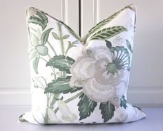 a white and green floral pillow sitting on top of a table