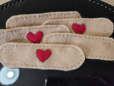 three pieces of felt with red hearts on them sitting on a black tablecloth covered plate