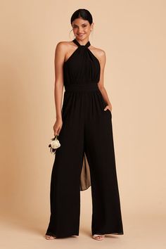 a woman wearing a black halter neck jumpsuit with high slits and flowers in her hand