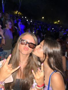 two women kissing each other in front of an audience at a music festival or concert