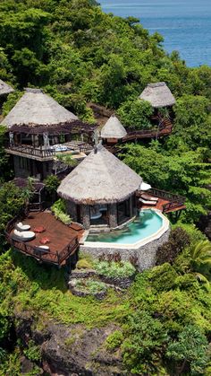 an aerial view of the resort and its surrounding pool area, with thatched huts