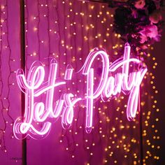 the words let's party are lit up in pink and white lights on a wall