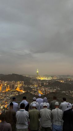 a group of people standing on top of a hill looking down at the city below