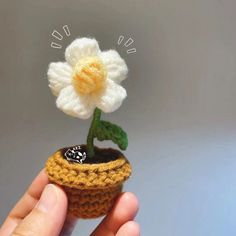 a small crocheted flower in a pot with a tiny white flower on top