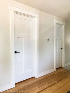 an empty room with two white doors and hard wood flooring on either side of the door