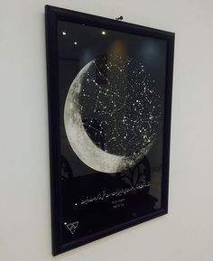 a black framed art piece hanging on the wall next to a window with stars and moon in it