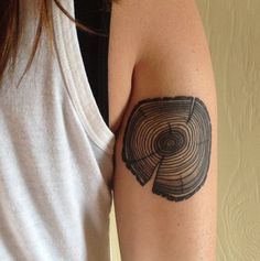 a woman with a tattoo on her arm that has a tree trunk in it's center