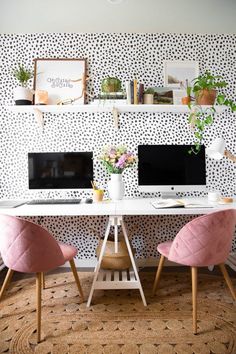 two pink chairs sit at a white desk in front of a black and white wall