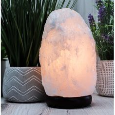 a himalayan salt lamp sitting on top of a wooden table next to potted plants