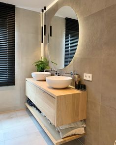 a bathroom with two sinks and a large round mirror above the sink in front of it