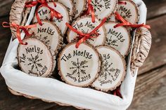 christmas ornaments are arranged in a basket on a wooden table with red ribbon around them