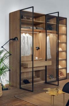 an open closet with clothes hanging on the shelves, and a chair next to it