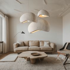 a living room filled with furniture and lamps hanging from the ceiling over it's windows