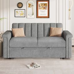 a gray couch with two brown pillows and pictures on the wall