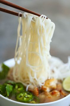 a close up of a bowl of noodles with chopsticks sticking out of it