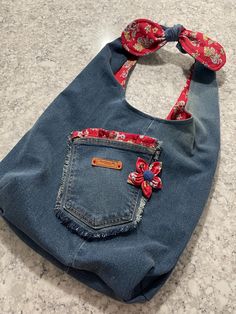 a denim bag with a red flower on the front pocket and a bow in the back