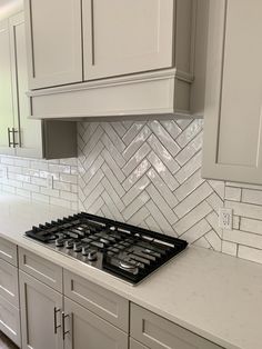 a stove top oven sitting inside of a kitchen next to white cabinets and counter tops