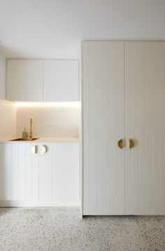 an empty kitchen with white cupboards and gold pulls on the door knobs,