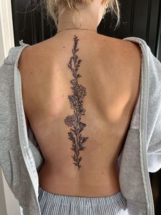 the back of a woman's neck with flowers tattooed on her upper and lower back