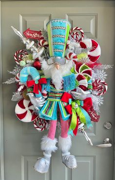 a christmas wreath hanging on the front door decorated with candy canes and santa claus