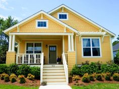 a yellow house with white trim on the front door and steps leading up to it