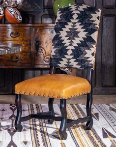 an upholstered chair sits in front of a wooden dresser and patterned rug on the floor