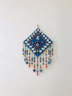 a blue and white wall hanging with beads on it's face, in the shape of a diamond