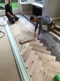 two men working on wood flooring in a room with hardwood floors and hard surfaces