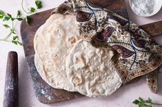 three pita breads sitting on top of a cutting board next to a knife