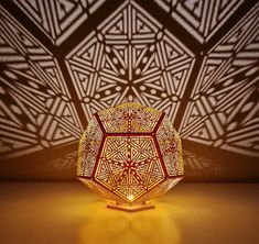 an intricately designed lamp is lit up on the floor in front of a wall