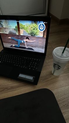 an open laptop computer sitting on top of a wooden table next to a cup of coffee