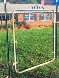 a fence that is in front of a house with a green yard and brick building behind it