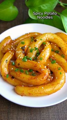 spicy potato noodles on a white plate with green garnish and seasoning sprinkles