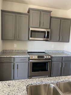 a kitchen with gray cabinets and stainless steel appliances