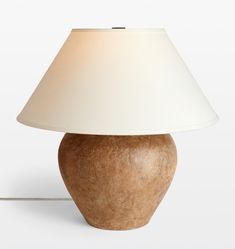 a lamp with a white shade on it sitting next to a light bulb in the shape of an apple