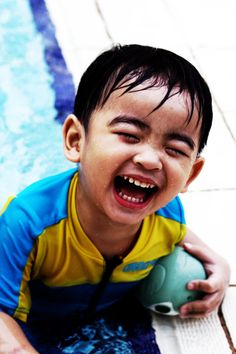 a little boy that is holding a ball in his hand and smiling at the camera