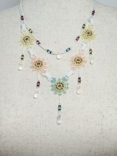 a woman wearing a necklace with flowers and beads hanging from it's neckline