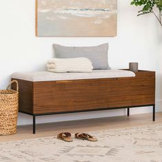 a bed with a wooden frame and footstool in front of a painting