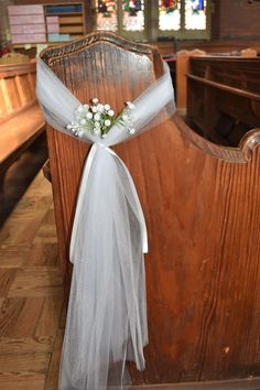 a church pew decorated with white flowers and tulle for the bride's wedding