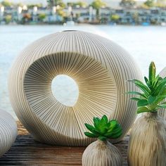 three vases sitting on top of a wooden table next to each other near the water