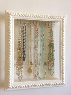 a white frame holds several necklaces and bracelets on display in a jewelry holder