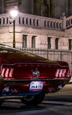 a black and white photo of an old mustang parked in front of a building at night