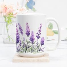 a white coffee mug with purple flowers painted on the outside and inside, sitting on a marble coaster