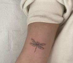 a small dragonfly tattoo on the arm