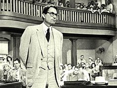 a man in a suit and tie standing in front of a room full of people