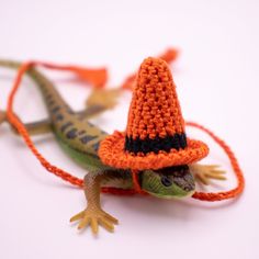 an orange and black crocheted lizard wearing a witches hat