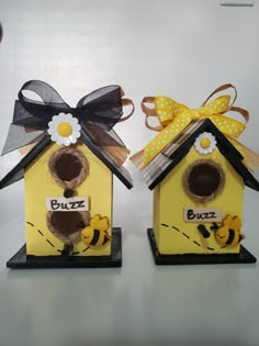 two yellow birdhouses with black and white bows on them, one has the word buzz written on it