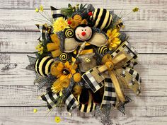 a yellow and black wreath with a teddy bear, sunflowers and a bee