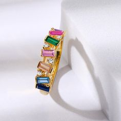 Stand out of the crowd with this beautiful yellow gold plated & multi-coloured ring. It is precisely crafted from yellow-gold plated 925 Sterling silver and adorned with seven colourful stones in bar and prong settings. Thanks to the stones brilliant emerald cut, they harmonize perfectly with the high-quality piece of jewelry and sparkle in rainbow colors. It almost seems like they are dancing on the jewel. The glamorous stones glimmers in the light revealing a rainbow of colours. Thanks to the Yellow Gold-plated Ring Jewelry, Yellow Gold Plated Ring Jewelry, Gold Multi-stone Crystal Ring Gift, Gold Multi-stone Crystal Promise Ring, Gold Multi-stone Crystal Ring As A Gift, Elegant Rainbow Ring Jewelry, Elegant Rainbow Colored Ring Jewelry, Elegant Rainbow Colored Ring, Gold Multi-stone Fine Jewelry Rings