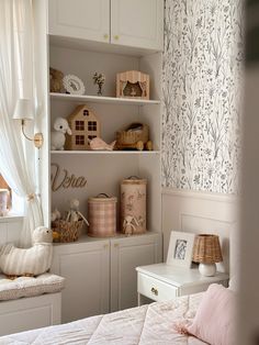 a bedroom with white furniture and floral wallpaper on the walls, along with pink pillows